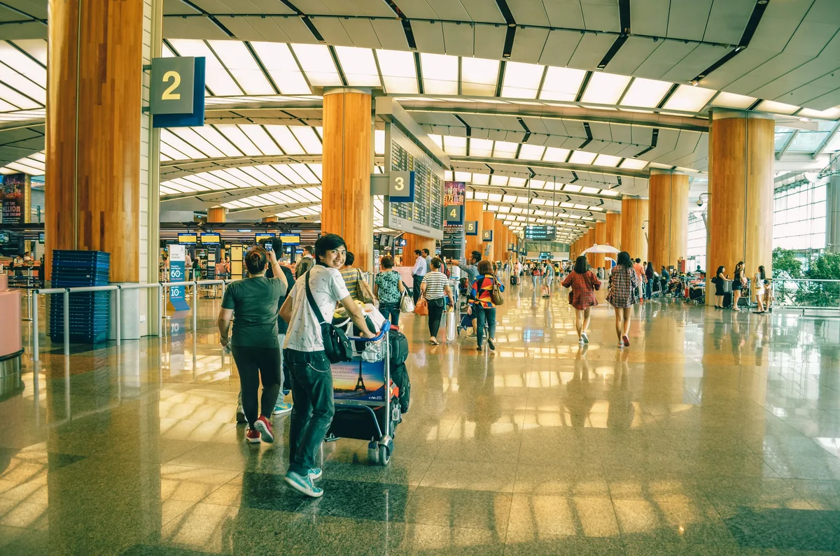 A traveller with a luggage trolley in an airport hall